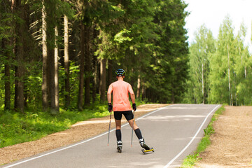 A man rides roller skis in a summer park.Cross country skiing.