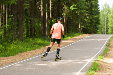 Fototapeta premium A man rides roller skis in a summer park.Cross country skiing.