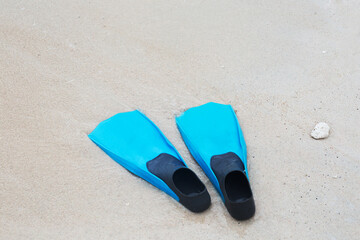Fototapeta na wymiar Two blue flippers on a sandy beach, side view