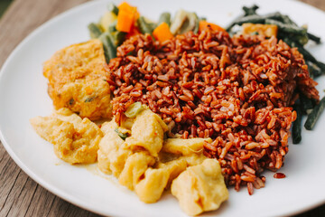 Brown rice with vegetables, beans and scrambled eggs close-up. Delicious Asian lunch on a white plate