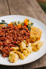 Delicious rice with vegetables and scrambled eggs on a white plate. Tofu curry with beans for lunch
