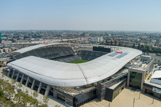 aerial shot of BMO Stadium at Exposition Park with lush green trees and grass and office buildings, retail stores and apartments in the city skyline in Los Angeles California USA