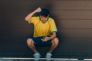 young man with mobile phone or smartphone and yellow t-shirt looking at mobile phone