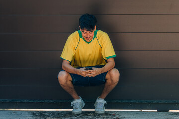 young man with mobile phone or smartphone and yellow t-shirt looking at mobile phone