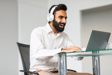 Deadline concept. Smiling indian man programmer networking and connecting to internet via laptop...