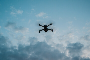 A high-tech drone in the sky. New dark grey drone quadcopter with digital camera and sensors flying