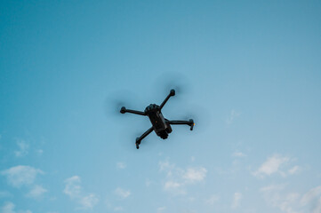 A high-tech drone isolated in the sky. New dark grey drone quadcopter with digital camera and sensors flying