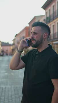 Vertical video of a young man answering a phone call on the street.