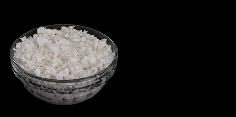 Cottage cheese in glass bowl isolated on black background. Side view of Wholesome curd snack