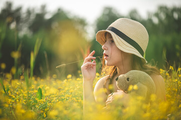 Dreamy pensive girl sitting in a field with yellow wildflowers