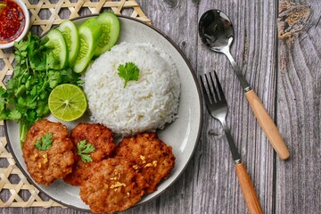Fried Chicken Rice on a white plate with a spoon and fork wooden background,top view