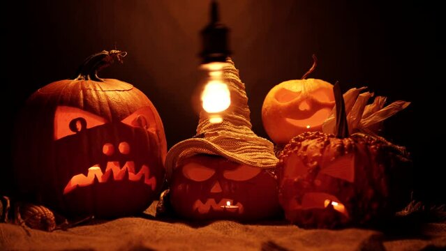 Infernal and mystical background of scary and mysterious carved Jack-o-lanterns with barn burlap and dry hay. Handmade arrangement of harvest, Halloween and spirits background with pumpkins.