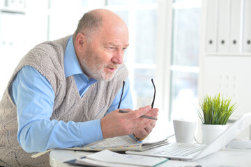 Emotional senior man reading newspaper at home