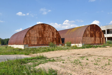 two hangars with a rusty roof
