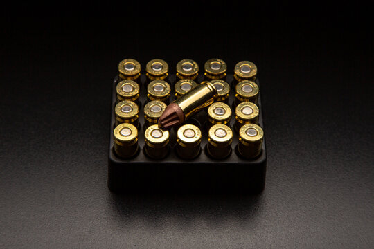 Pistol cartridges 9 mm on a smooth glossy surface with reflections. Ammunition for pistols and PCC carbines on a dark back.