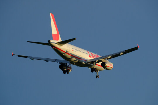 Airbus A320, operated by Lauda Europe, approaching the airport during sunset.