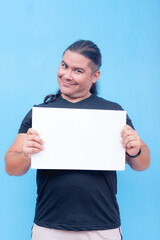 A smiling biracial male holding a blank placard with both hands and his head tilted. Isolated on a blue background