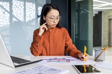 Serious thinking female financier on paper work, Asian concentrated writing data in forms, using...