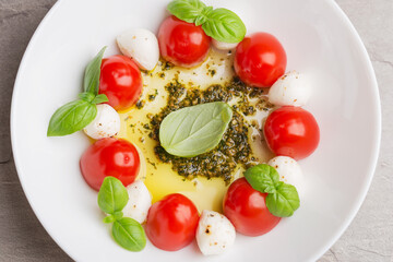 Obraz na płótnie Canvas Caprese salad with tomato, mozzarella, basil, olive oil, pesto sauce on white plate close up. Mediterranean cuisine. Italian food. Top view.