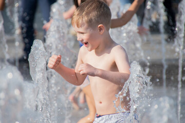 Child enjoying and cooling off in jet of water. Close up portrait. Sunny photo