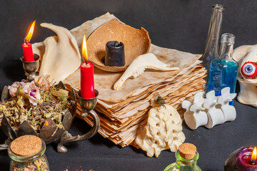Mystic occult witchcraft background with witch craft tools on old yellow parchment grimoire weathered pages, magic ritual. Halloween theme, goat jaw bones, black candles and raven toe for spells.
