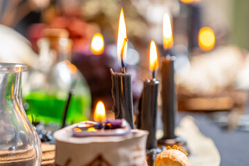 Witchcraft altar selective focus to details of candles light and magic tools or items.  Halloween and occult black magic ritual. Magic practice symbolism. Ritual scene in dark frightening atmosphere. - 631932489