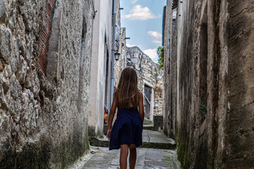 A girl walking through historical narrow street in Vrgada, Croatia