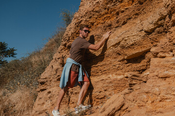 Confident male adventurer holding on grip while climbing the rock as extreme challenge