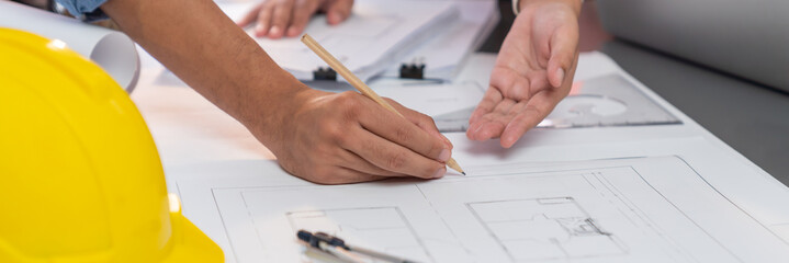 Engineer partner drawing and working on blueprint design together on office table for architectural...