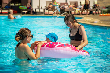 Children with mom have fun in the pool on a hot summer day.