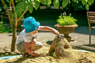 A little boy plays alone in the sandbox.