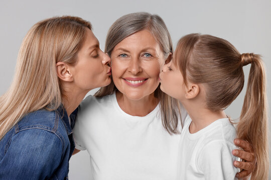 Three generations. Happy grandmother, her daughter and granddaughter on light gray background