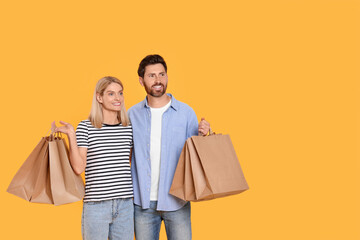 Family shopping. Happy couple with paper bags on orange background. Space for text