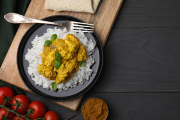 Delicious rice with chicken curry and products on grey wooden table, flat lay. Space for text