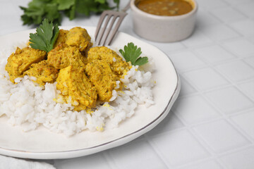 Delicious rice and chicken with curry sauce on white tiled table, closeup. Space for text