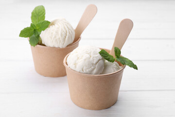 Delicious vanilla ice cream and mint on white wooden table, closeup