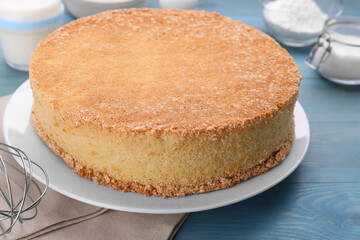 Plate with delicious sponge cake on light blue wooden table, closeup
