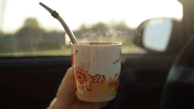 hombre bebiendo taza de mate caliente viajando en coche en la carretera