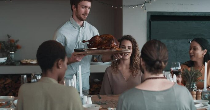 Turkey, serving lunch and friends at a party for food, conversation and celebration. Happy, home and a man with a chicken or meat for dinner with a group of people to celebrate Christmas or a holiday