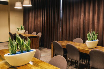 View of the room interior with a wood tables, chairs, brown curtains.