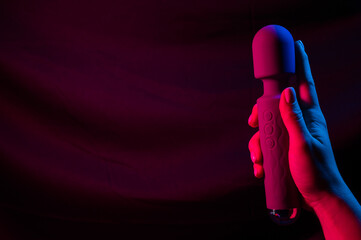 Woman holding a vibrator in neon pink and blue light.
