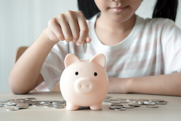 Obraz na płótnie Canvas Little girl putting her coin into pink piggy bank concept of saving money for future plan.