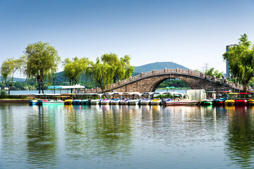 Fototapeta na wymiar Small bridge and pleasure boats in an outdoor park in the city