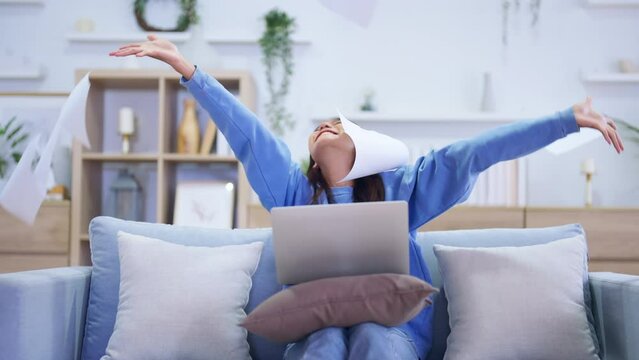 Young Asian Woman Thrilled with Success, Celebrating Victory at Home. Happy Female Using Computer Laptop and Paper Toss