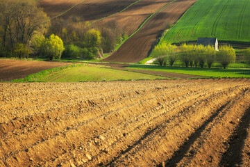 Fototapeta premium Beautiful spring rural landscape with plowed fields and small house
