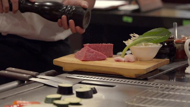 Japanese Chef add pepper to Kobe raw meat at Japan Luxury restaurant at Hyogo Kobe over wood table