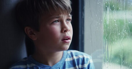 Rain, window and boy child thinking, sad and frustrated, depression and bored in his house. Mental health, winter weather and face of male teen kid with anxiety and unhappy emotion with storm at home