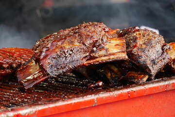 Cooking BBQ pork ribs and chicken on wire wrack in fire.