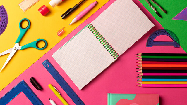 Сomposition of multi-colored stationery items laid out on the table. office, school FLAT LAY pink, yellow, green background. Copy space notebook