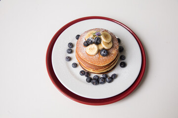 Pancakes stack with banana and blueberries topping and bee honey breakfast food